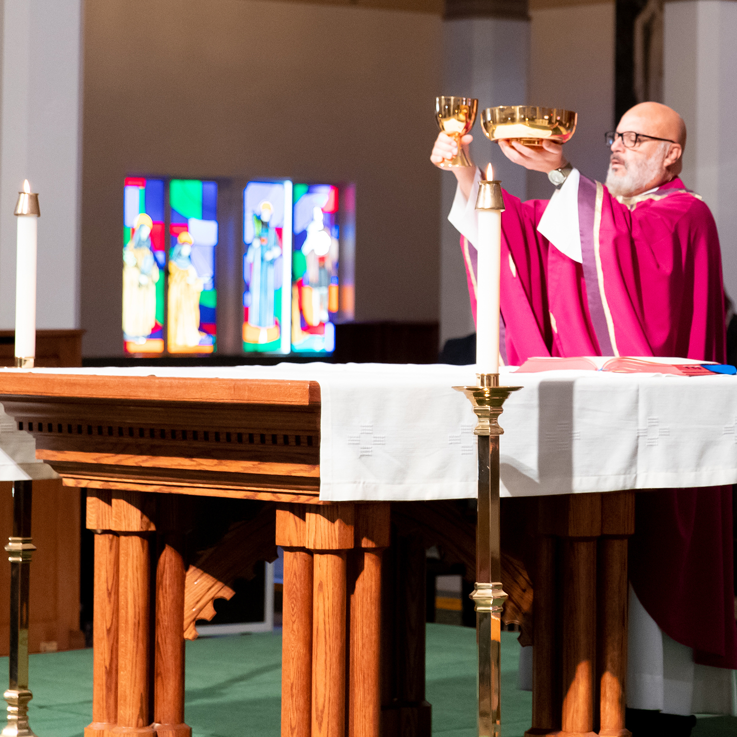 a priest holding up a golden chalice and paten